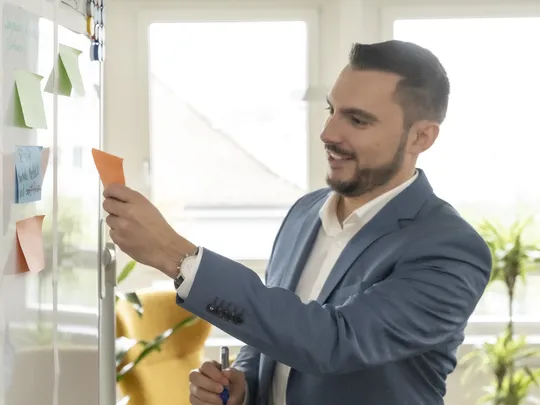 Mitarbeitender von Bosshard & Partner steht am Whiteboard und hält ein Stift und ein Zettel.
