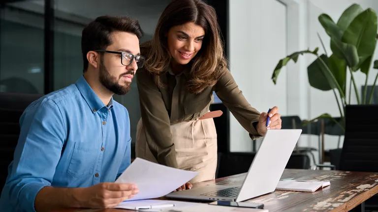 Woman and man working togheter in a office wtih notebook